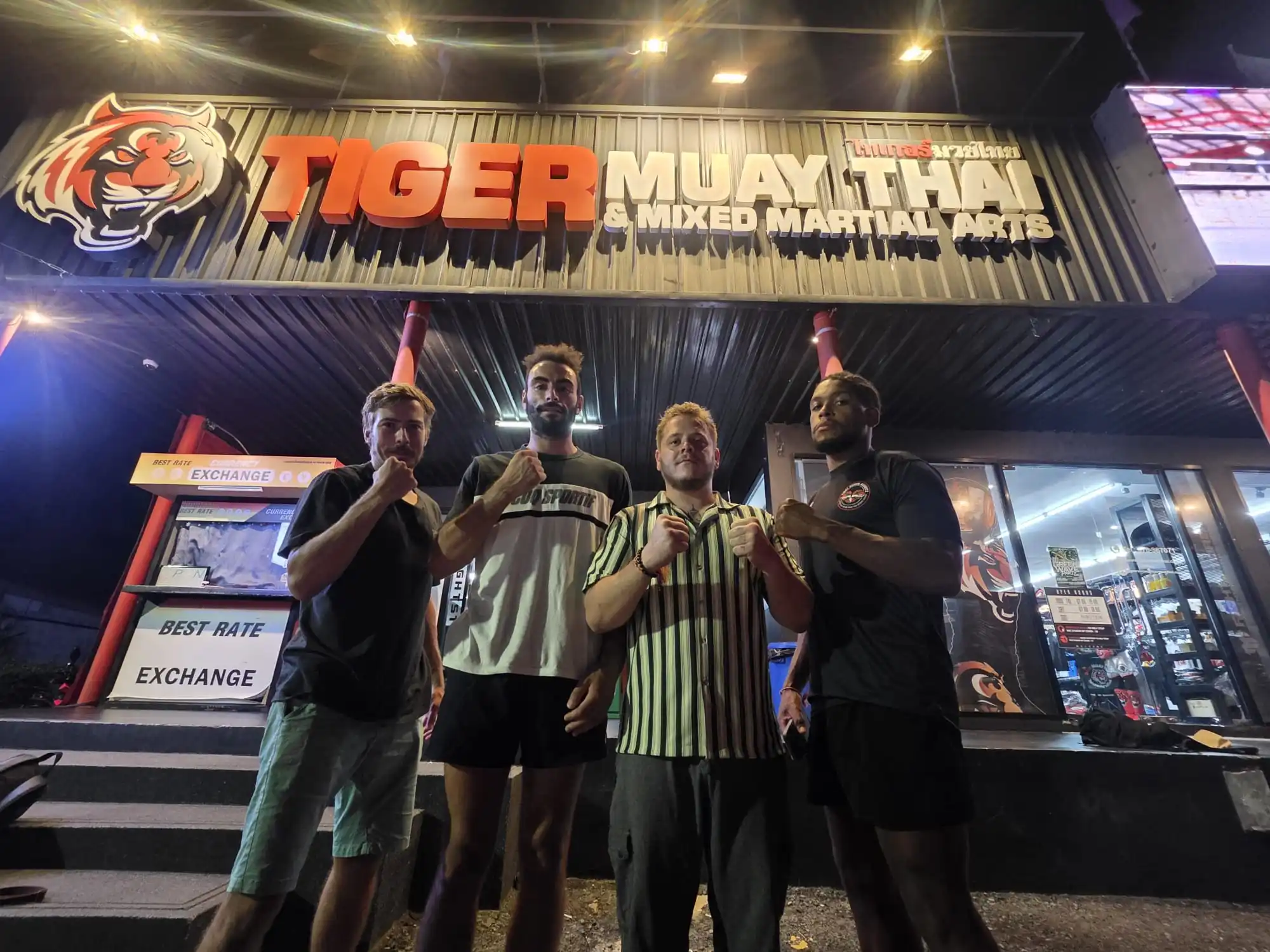 Les compétiteurs devant l'enseigne du camp Tiger Muay Thaï et MMA